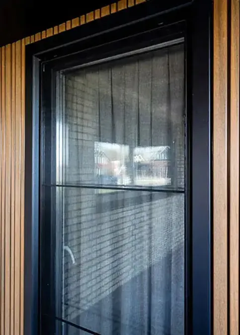 Houten kozijn met zwart metalen raamwerk en verticale gevelbekleding van hout, geplaatst door Kozijnenmeester.