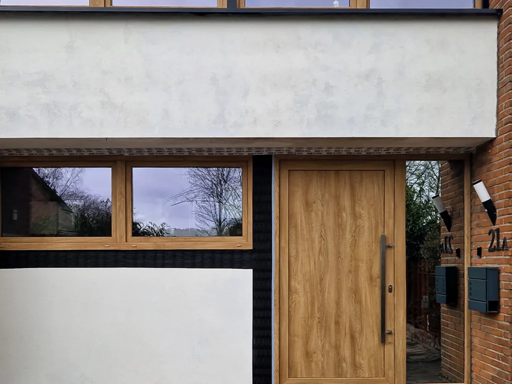 Moderne voordeur en raamkozijnen van hout in een strakke gevel.